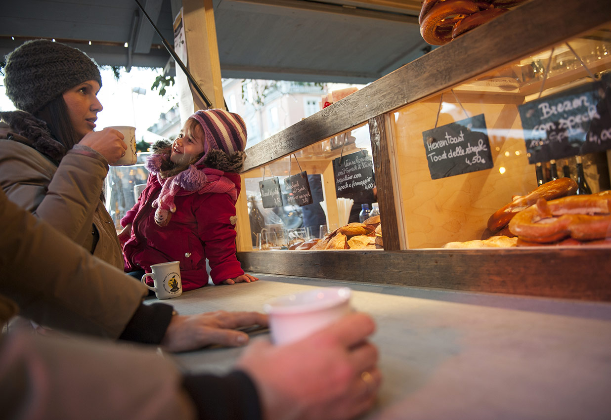 Una famiglia beve e mangia a uno stand gastronomico del Mercatino di Natale di Bolzano